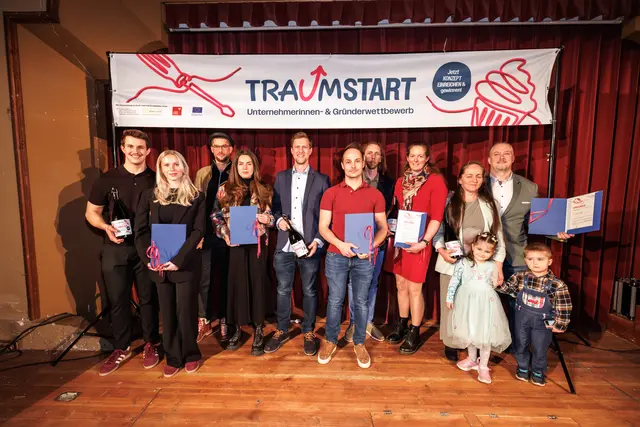Die Gewinnerinnen und Gewinner der ersten "Traumstart"-Runde bei der Preisverleihung im März 2026: Lukas Harringer, Sarah Hnáthová, Christoph und Arnela Brunner, Josef Haas, Johannes Heim, Andreas Prosch, Serima Wildvank sowie Erika und Zoltan Lauscher mit Familie (v. li.). | Foto: Maximalgrafik/Maximilian Köck