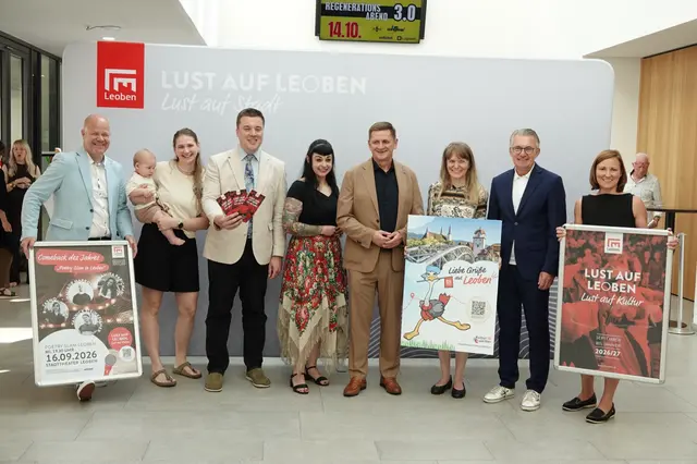 4 Männer, 4 Frauen und ein Baby stehen nebeneinander und halten 3 Transparente 