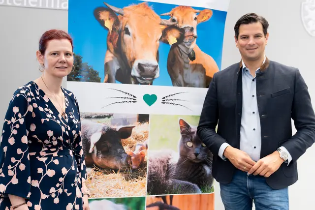 Zwei Personen stehen vor einem Plakat.