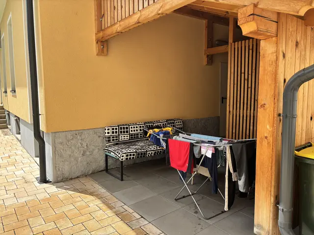 Sitzbank im Außenbereich, daneben steht ein Wächeständer.