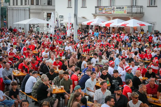 Menschenmassen sitzen auf Bierbänken am Hauptplatz zum Public Viewing