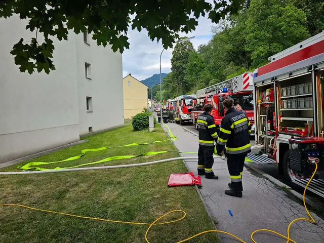 Feuerwehrmänner stehen vor mehreren Einsatzwägen, Schläuche sind verlegt