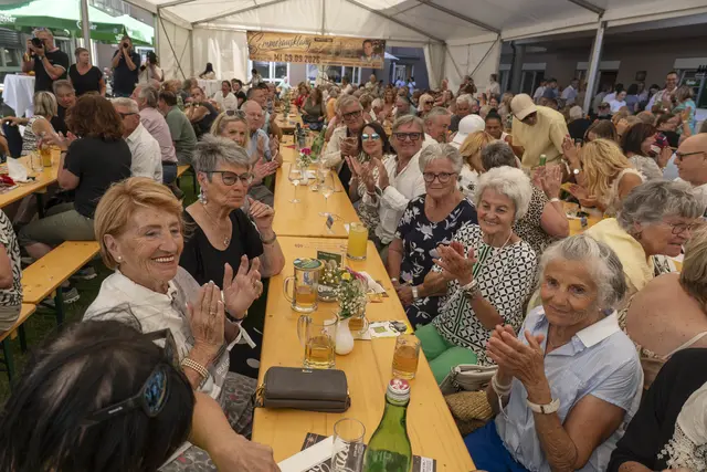 Menschen sitzen auf Bierbänken und feiern.