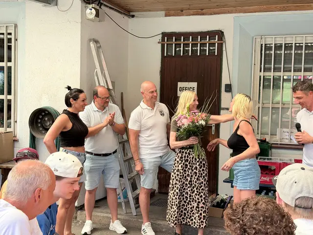 3 männer und 3 Frauen im Bild, einer Frau werden Blumen überreicht. 