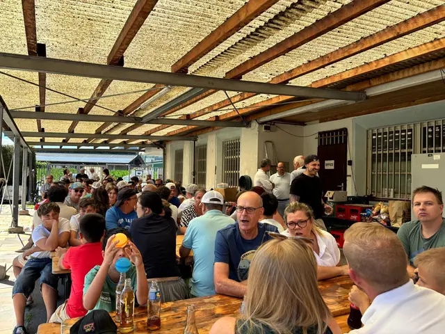 Viele Menschen sitzen zusammen bei einem Sommerfest und unterhalten sich