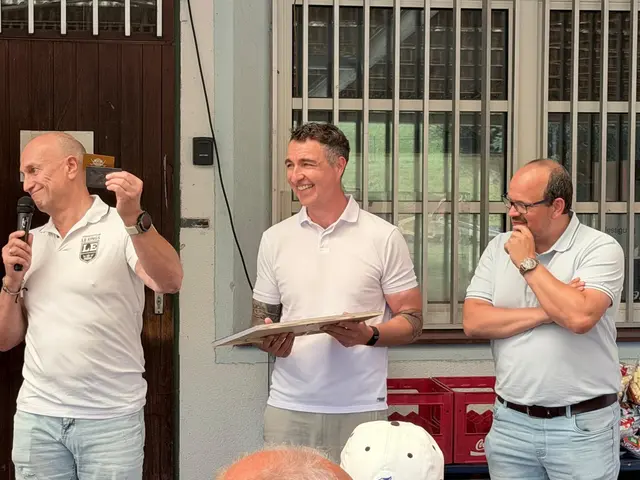 3 Männer, einer hält eine goldene Karte und einer ein Bild