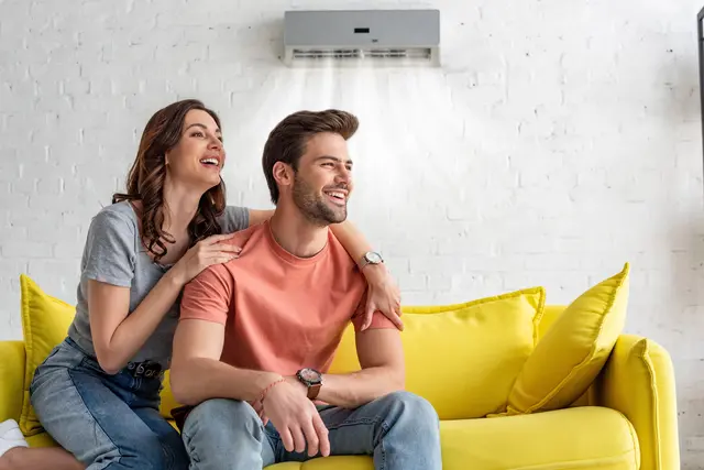 Ein Paar sitzt auf einem Sofa und genießt die kühle Luft aus der Klimaanlage.