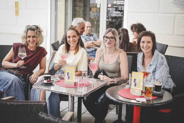 4 Frauen sitzen an einem Tisch und trinken Wein