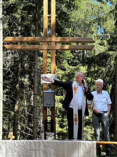 Pfarrer Peter Weberhofer segnet das Gipfelkreuz und erklärt die Bedeutung eines Kreuzes