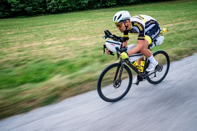 Ein Radfahrer fährt in hoher Geschwindigkeit auf einer Asphaltstraße