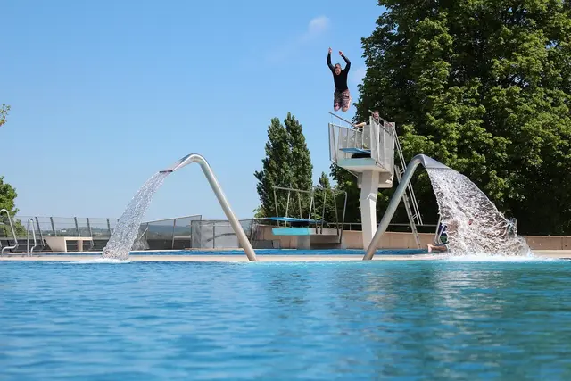 Person springt von Sprungturm ins Wasser