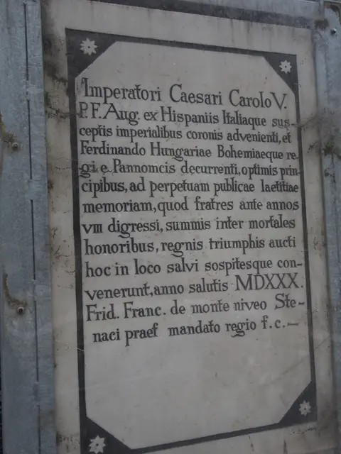 Fotografie einer rechteckigen, hellen Steintafel. Die Gedenktafel zeigt eine historische, sauber eingemeißelte Inschrift in lateinischer Sprache.