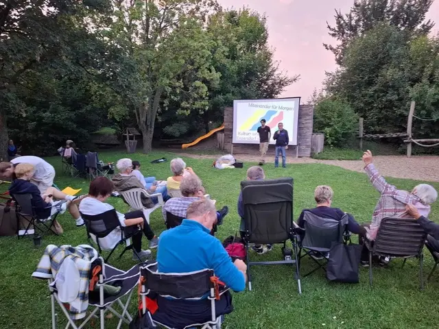 Publikum auf Wiese vor Leinwand