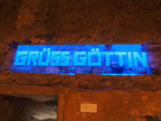Eine von Ursula Beiler gestaltete Tafel mit der Aufschrift „Grüß Göttin“ in blauer Leuchtschrift, montiert an den historischen Steinmauern der Festungsanlage Altfinstermünz für die Ausstellung „Widerstand ist alles“.