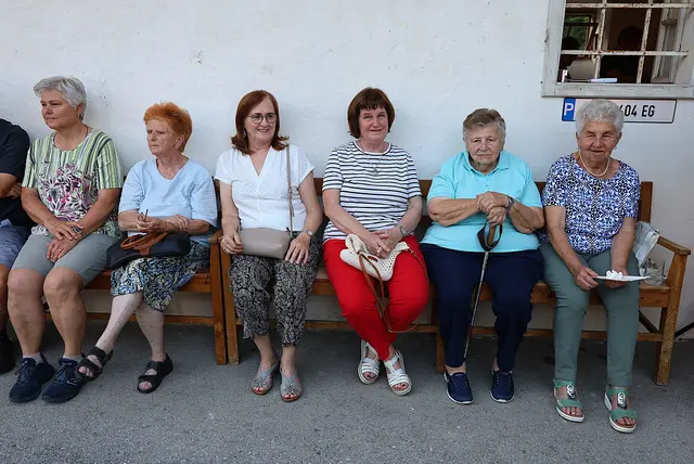 Frauen sitzen auf einer Holzbank.