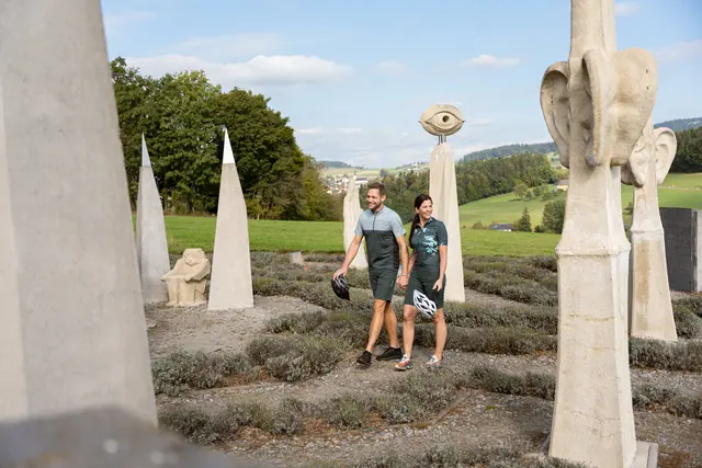Mitten im Labyrinth Hofkirchen an der Penzensteinrunde des Escape Trails Neustift betrachtet das Pärchen die steinerne Skulpturen.  | Foto: Tourismusverband Donau Oberösterreich/infilmity