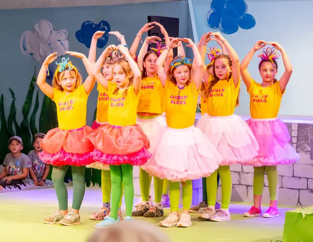 Kinder in Tüllröcken und gelben T-Shirts als Zauberblumen.