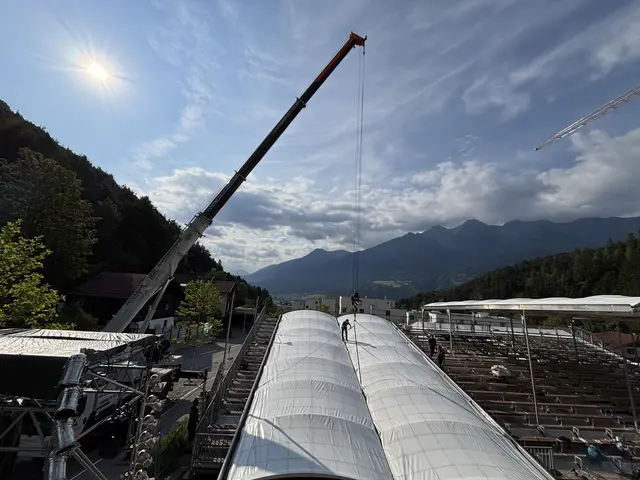 Ein Kran hebt Zentimeter für Zentimeter das tonnenschwere Dach über die Zuschauertribüne.  | Foto: Georg Larcher