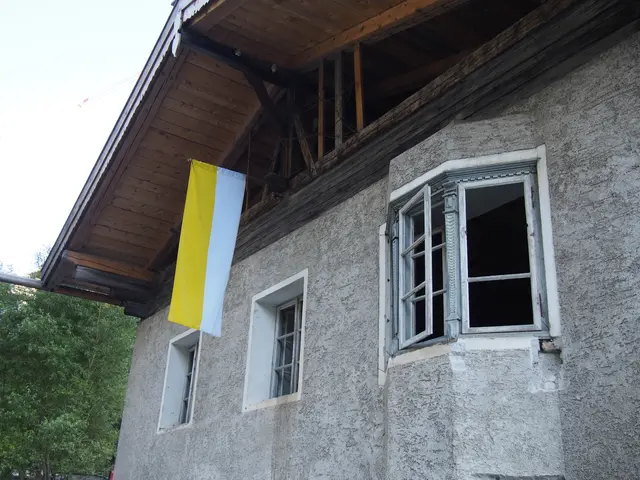 Außenaufnahme des benachbarten Widums am Lueg während der Renovierungsarbeiten mit Baustellengerüst und einer festlich gehissten Kirchenfahne in Gelb-Weiß.