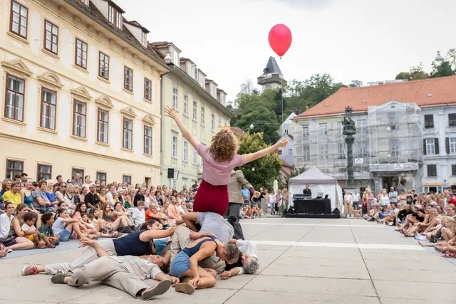 Künstlerinnen und Künstler performen auf einem großen Platz vor Publikum. 