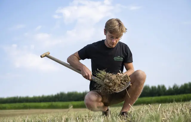 Valentin Seiringer auf einem Feld mit einem Spaten mit Erde