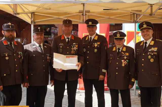 Feuerwehrkamerad mit Urkunde und Feuerwehrkollegen