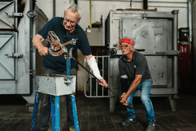 Der Glaskünstler Rudolf Weninger (l.) begann vor 71 Jahren seine Lehre in der Stoelzle-Glasfabrik. In der Schauglashütte zeigt er zusammen mit seinem langjährigen Glaskünstler-Kollegen Heinz Strasser interessierten Gästen des Glas-Centers, wie dieses Handwerk gelebt wird. | Foto: Bernd Grosseck