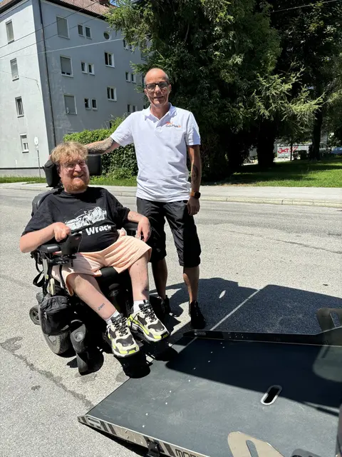 Seit Mai 2026 ist Raphael Grothe vorwiegend in und um Salzburg mit seinem barrierefreien Taxi unterwegs. Über eine Rampe kann er den E-Rollstuhl von Jasmin direkt ins Fahrzeug befördern. | Foto: Lisa Gold