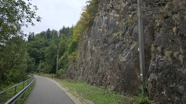 Auf einer Länge von rund 60 Metern werden Felswand und darunterliegende Grünfläche für den neuen Klettergarten vorbereitet. Zum Radweg hin wird mit einem Zaun abgesichert.  | Foto: Tauderer