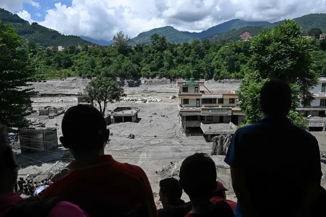 Menschen beobachten von einem Dach aus die von Schlamm umgebenen Häuser in Trishuli im nepalesischen Distrikt Nuwakot. | Foto: APA-Images / AFP / ARUN SANKAR