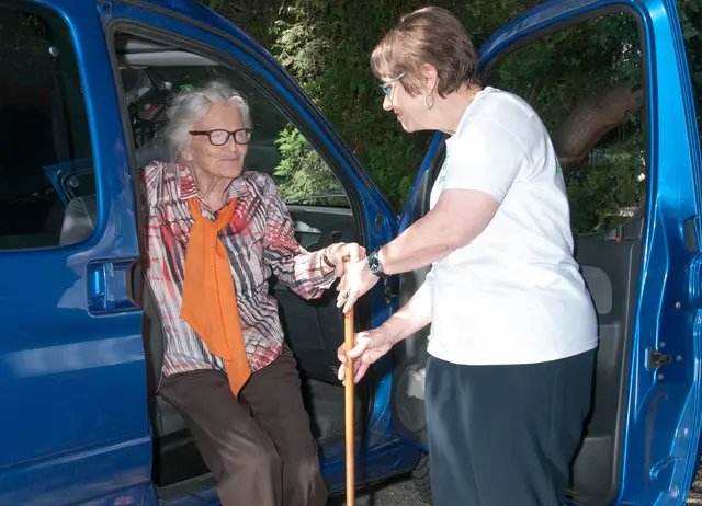 Frau hilft Seniorin aus dem Auto