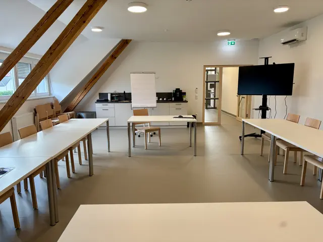 Ein großflächiger Raum mit Tischen und Sesseln sowie technischem Equipment ist zu sehen.