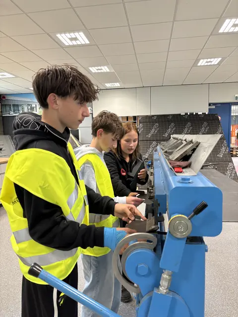 Jan Weratschnig und Edin Hasanovic bekommen von dem Lehrmädchen die Maschine erklärt. | Foto: Martina Schweller