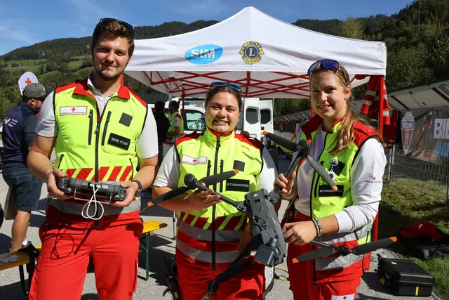 Lukas, Simone und Anna vom Roten Kreuz mit den Suchdrohnen. "Mit den Suchdrohnen werden zum Beispiel Lagebilder bei Naturkatastrophen wie Überschwemmungen erstellt. Und sie dienen zur Personensuche in unwegsamen Gelände", erklärte Lukas mit der Steuerung in der Hand. | Foto: Agnes Etzer