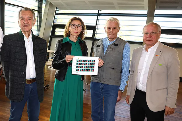 Drei Männer und eine Frau, die Briefmarken in der Hand hält