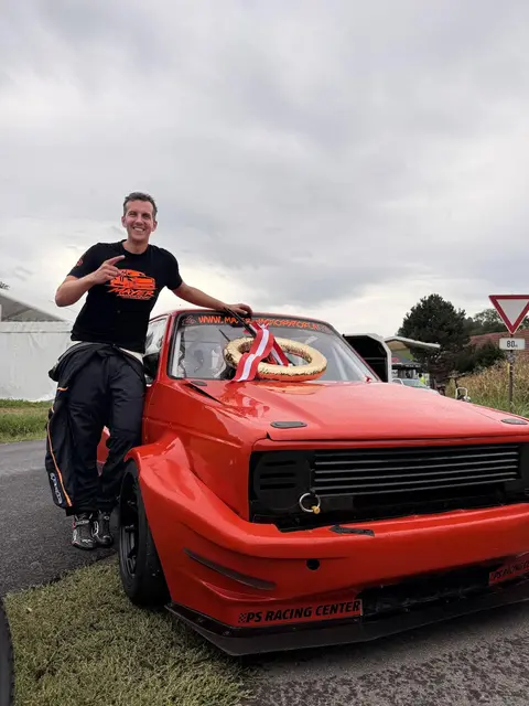Mann mit Siegerkranz und Auto