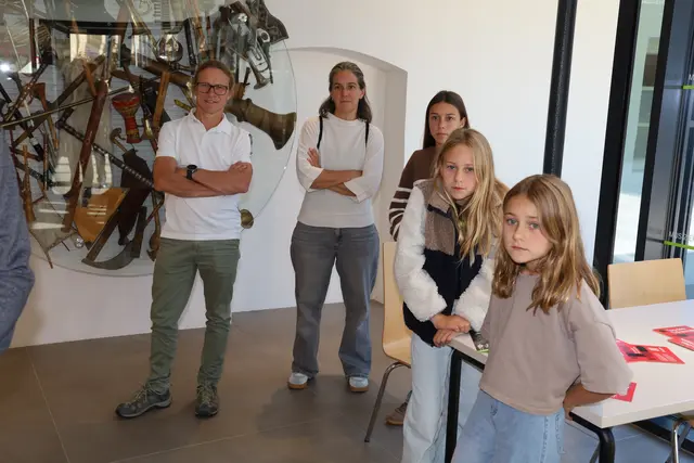 Zwei Erwachsene, eine Jugendliche und zwei Kinder stehen in einem Gebäude.