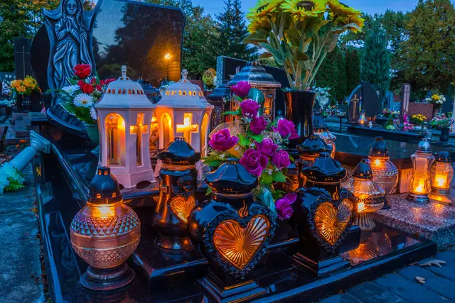 Brennende Kerzen und Blumen auf Gräbern
