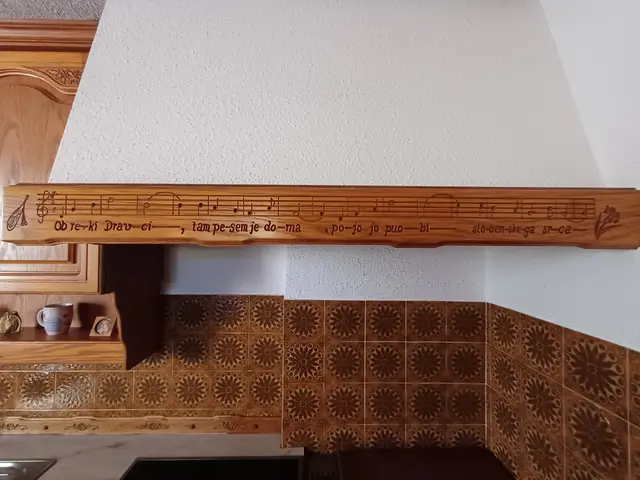 „Ob reki Dravci“ (Text: Milka Hartmann, Komposition: Hanzi Artač) die erste Zeile des Siegerliedes 1979 in Števerjan, verewigt in einer Schnitzerei in der Küche von Familie Artač. | Foto: Privat