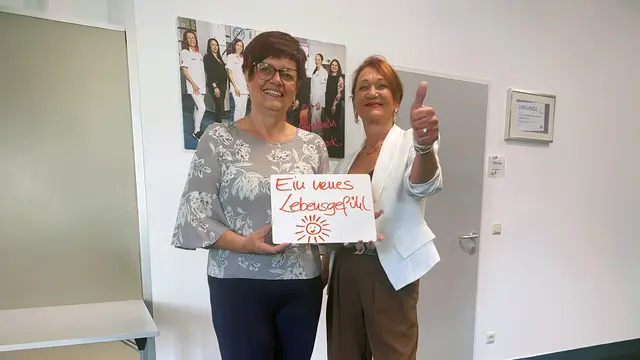 Silvia Hütter hält nach ihrer Abnahme von 22 Kilo im easylife Zentrum Graz ein Schild mit der Aufschrift „Ein neues Lebensgefühl“.