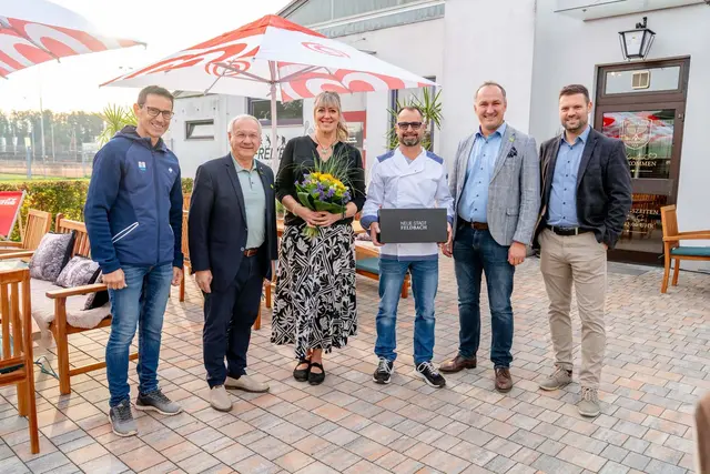 Fünf Männer und eine Frau stehen in einem Gastgarten.