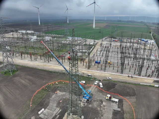 Strommast mit Kran, dahinter Umspannwerk