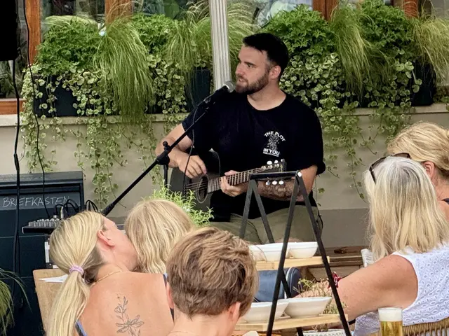Mann mit Gitarre und Mikro vor Publikum