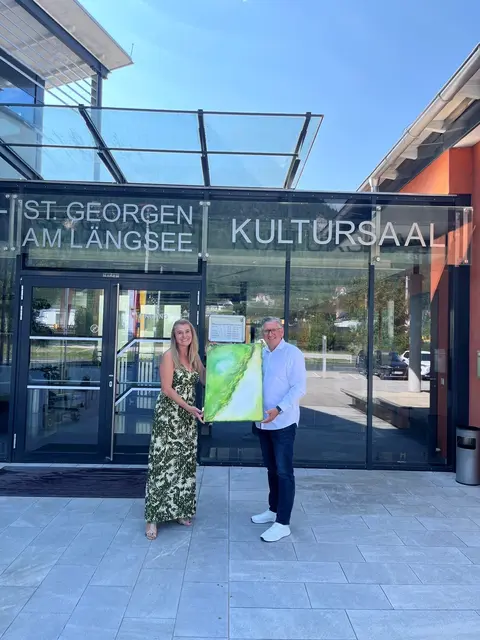Sozialpädagogin Barbara Edmonds möchte mit ihrer Kunst Bedürftigen in der Region helfen. Am Bild mit Ewald Göschl, Kulturreferent der Gemeinde St. Georgen. | Foto: Gemeinde St. Georgen am Längsee