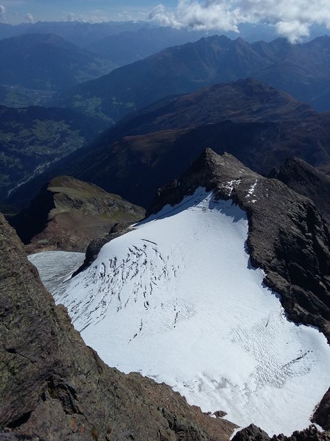 Ausblick vom Hohen Riffler (3168m-Verwallgruppe) hinunter zum Flirscher Ferner, in weiterer Folge bis zu den Ausläufern dieser Gebirgsgruppe bis zur Pezinerspitze, eine Reihe weiter hinten die Ausläufer der Samnaungruppe, dahinter ein Teil des Kaunergrats sowie die Ötztaler Alpen im Hintergrund. Am linken Bildrand sind zu sehen: Strengen und ein Teil vom Strengerberg, dahinter der Talort Landeck und das Venetmassiv. 