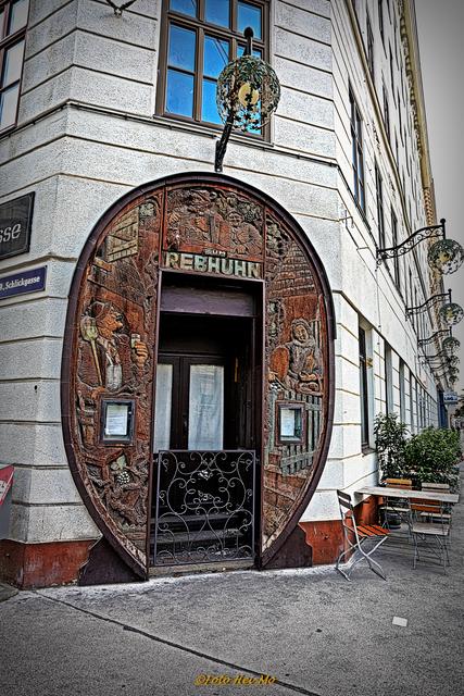 Dieser Eingang wird zwar nicht mehr benützt (jetzt ist er an der Seite), aber originell ist er.. ;) Man beachte auch die Lampen aus Schmiedeeisen. Diese Weinlaub-Lampen waren sehr beliebt, heute sind sie eher selten. 