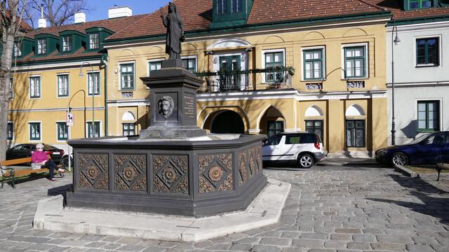 Der 1833 in der Mitte des Platzes aufgestellte und im Jahr darauf eingeweihte Brunnen spendete Wasser erst der Albertinischen Wasserleitung, später der Kaiser-Ferdinands-Wasserleitung. 1912 wurde der Brunnen an den nördlichen Rand des Platzes verlegt.
Dahinter das sog. Gaberschlössel, ehem. Gerichtsgebäude der Schottenherrschaft Breitenfeld
Der zweigeschoßige schlösschenartige Biedermeierbau wurde 1812 errichtet. Der Mitteltrakt ist leicht erhöht, die Fassade durch Lisenen gegliedert und mit Parapetreliefs im Obergeschoß verziert. Dem Portal in der Mittelachse ist eine Balkonvorhalle mit Spitzbogenarkaden vorgelagert. Im Obergeschoß befindet sich eine flache Mittelnische, die von ionischen Halbsäulen flankiert ist. Die schlichten Seitenteile tragen Dachhäuschen.