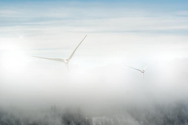 Die Windräder scheinen im Nebel zu schweben.