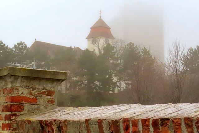 Die Kirche Alt Simmering im Winternebel, der versucht, das Hochhaus zu verschlucken