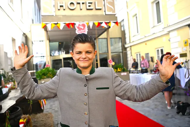 Thiemo Kanduth, der jüngste Sohn von Robert und Helvig Eva Kanduth, begrüßt die Gäste mit einem strahlenden Lächeln und offenem Wesen am roten Teppich vor dem Hotel Sandwirth. In festlicher Tracht zeigt er sich traditionsbewusst und dennoch ganz modern – ein sympathischer Auftritt des Nachwuchses einer der prägendsten Unternehmerfamilien Kärntens. | Foto: Josef Bodner